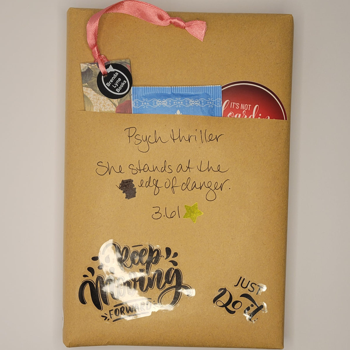 Hardcover book wrapped in brown paper with writing on it and goodies tucked inside.