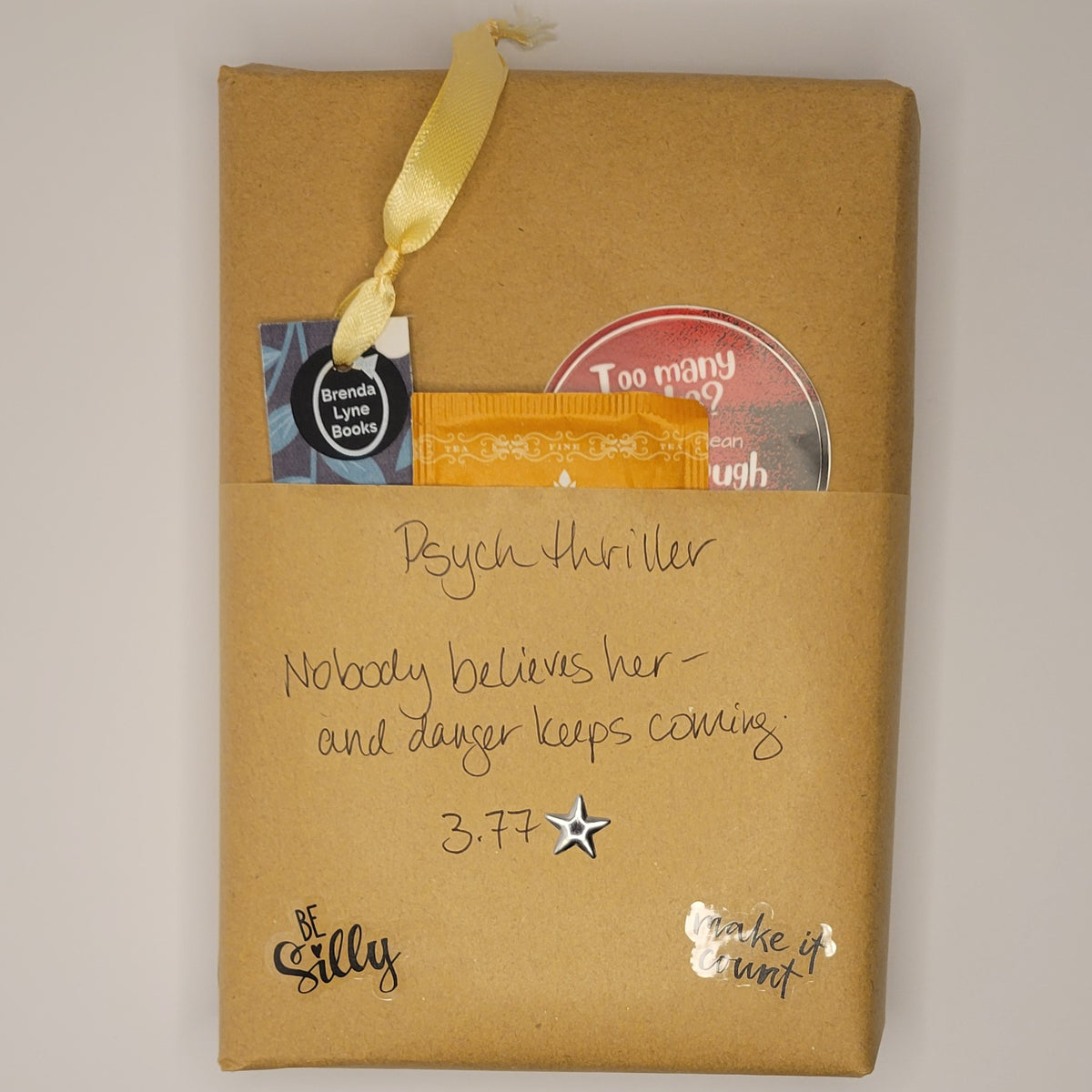 Hardcover book wrapped in brown paper with writing on it and goodies tucked inside.