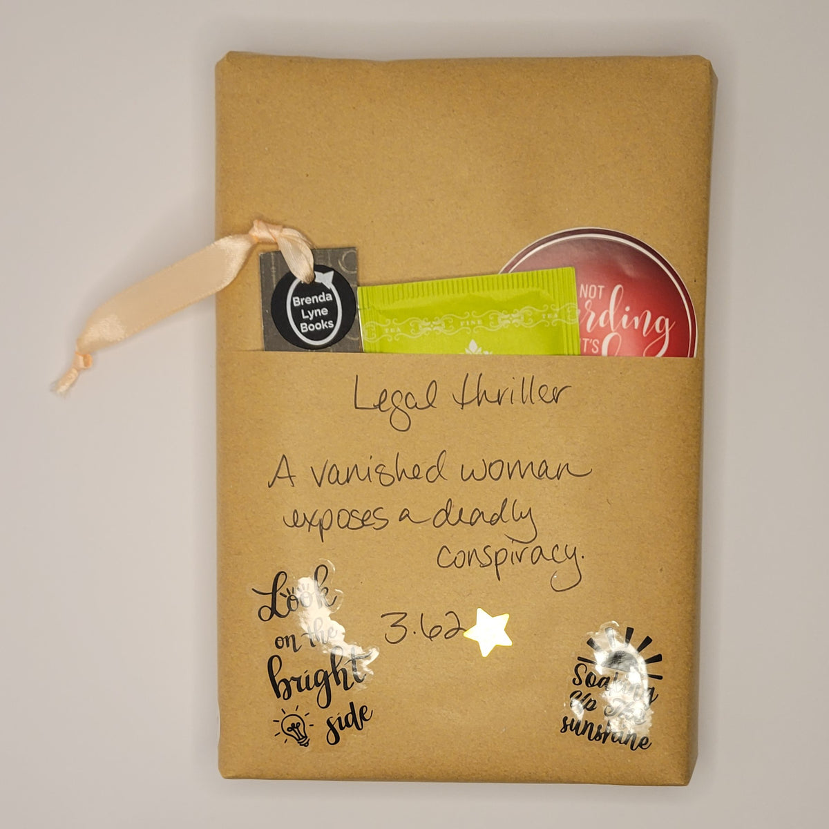 Hardcover book wrapped in brown paper with writing on it and goodies tucked inside.