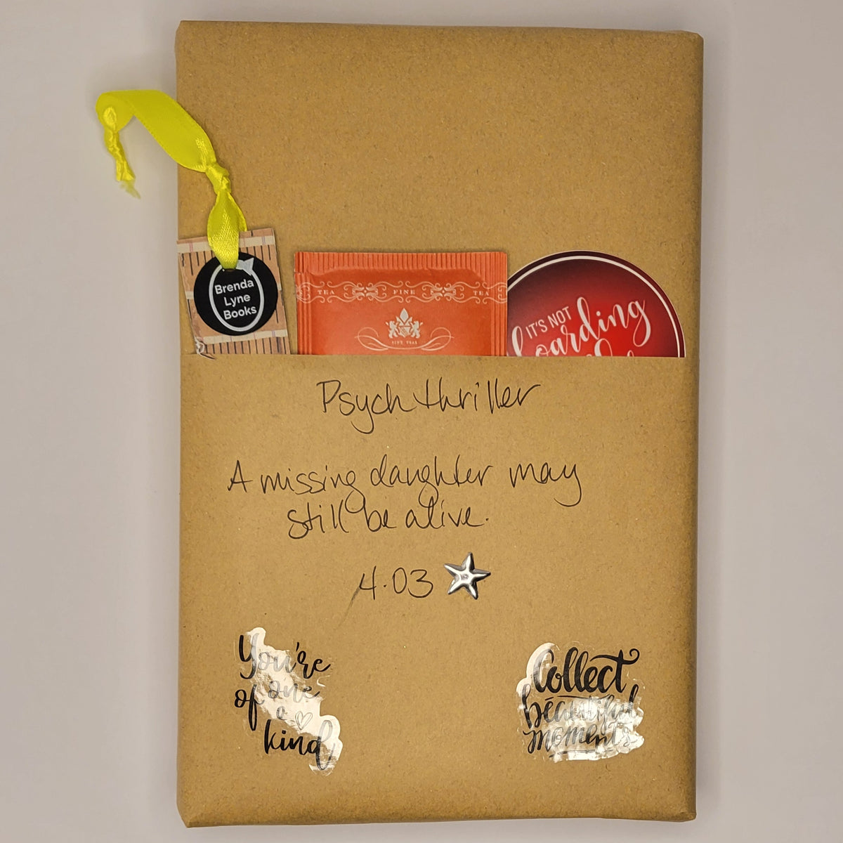 Hardcover book wrapped in brown paper with writing on it and goodies tucked inside.