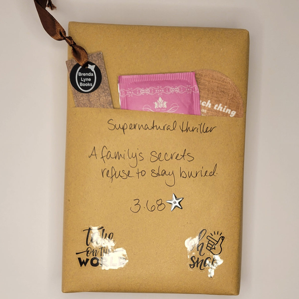 Hardcover book wrapped in brown paper with writing on it and goodies tucked inside.