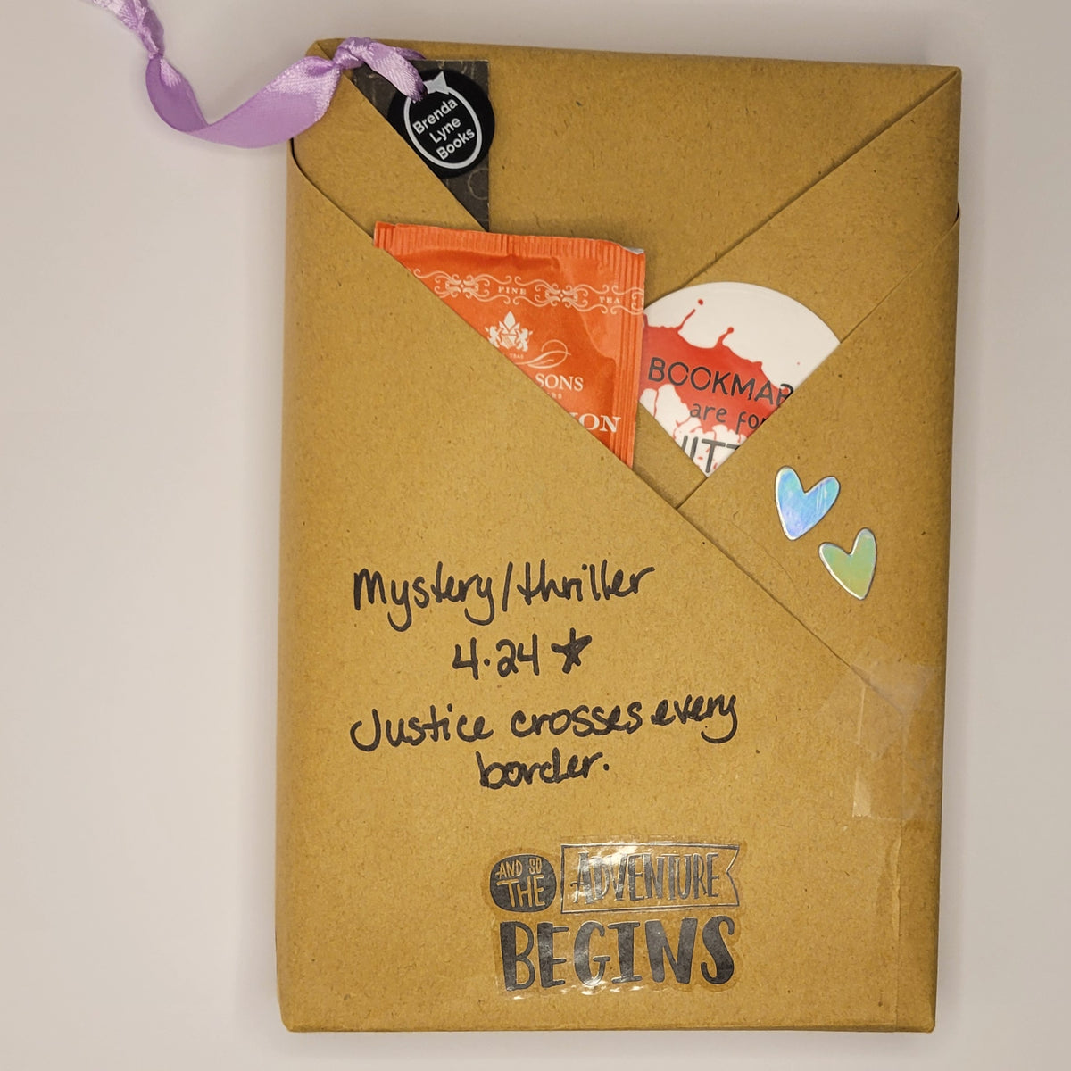Hardcover book wrapped in brown paper with writing on it and goodies tucked inside.