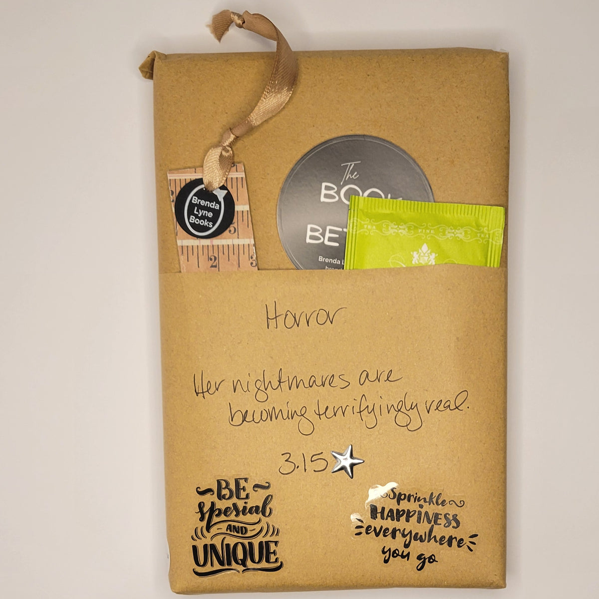 Hardcover book wrapped in brown paper with writing on it and goodies tucked inside.