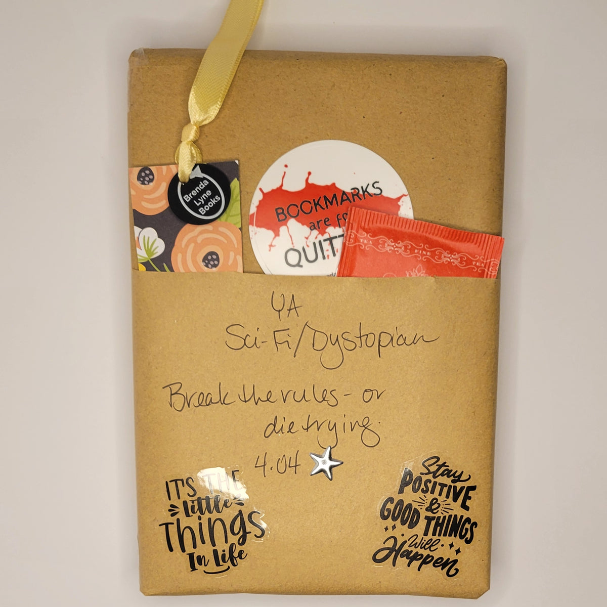 Hardcover book wrapped in brown paper with writing on it and goodies tucked inside.