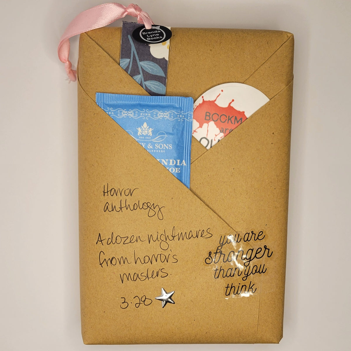 Hardcover book wrapped in brown paper with writing on it and goodies tucked inside.