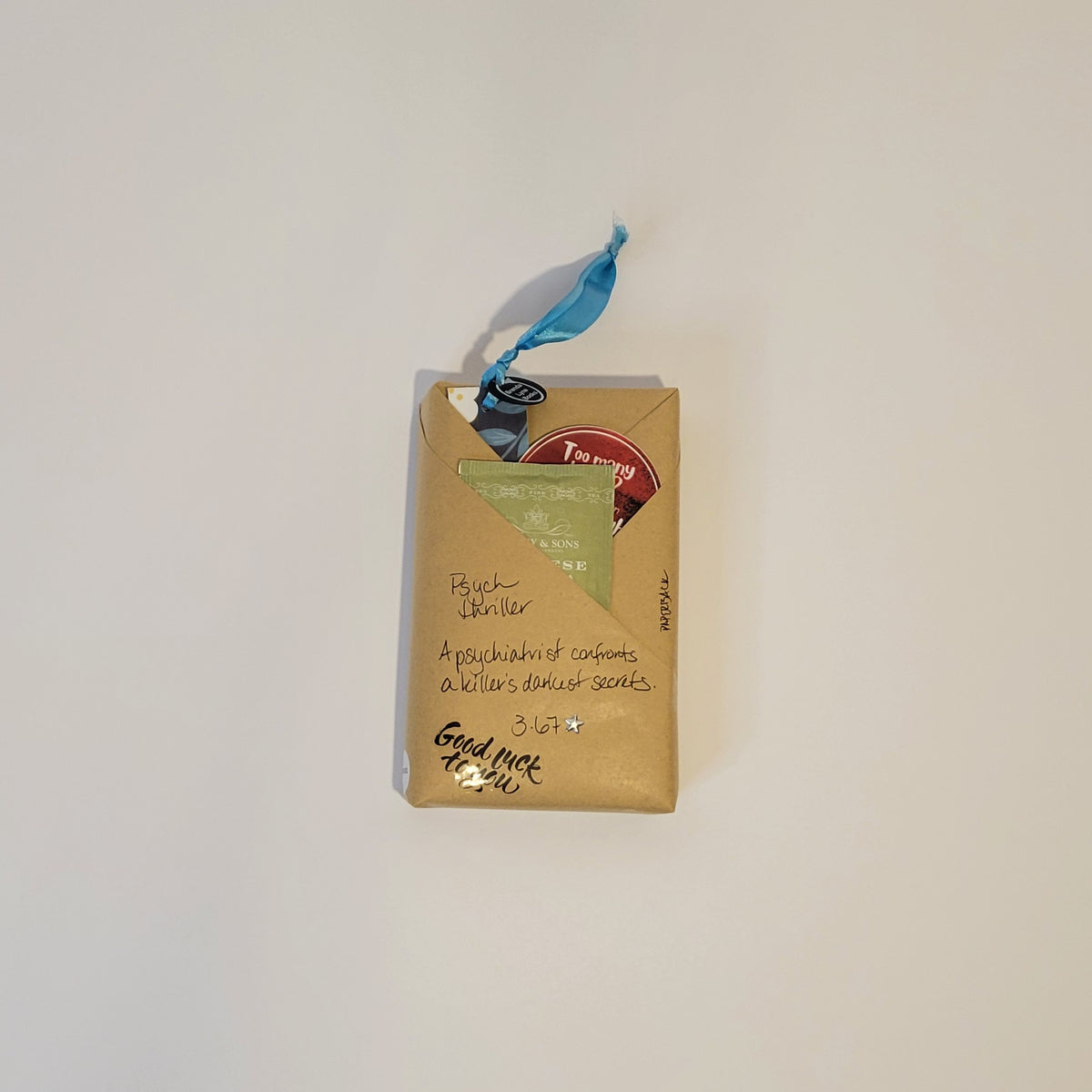 Paperback book wrapped in brown paper with writing on it and goodies tucked inside.