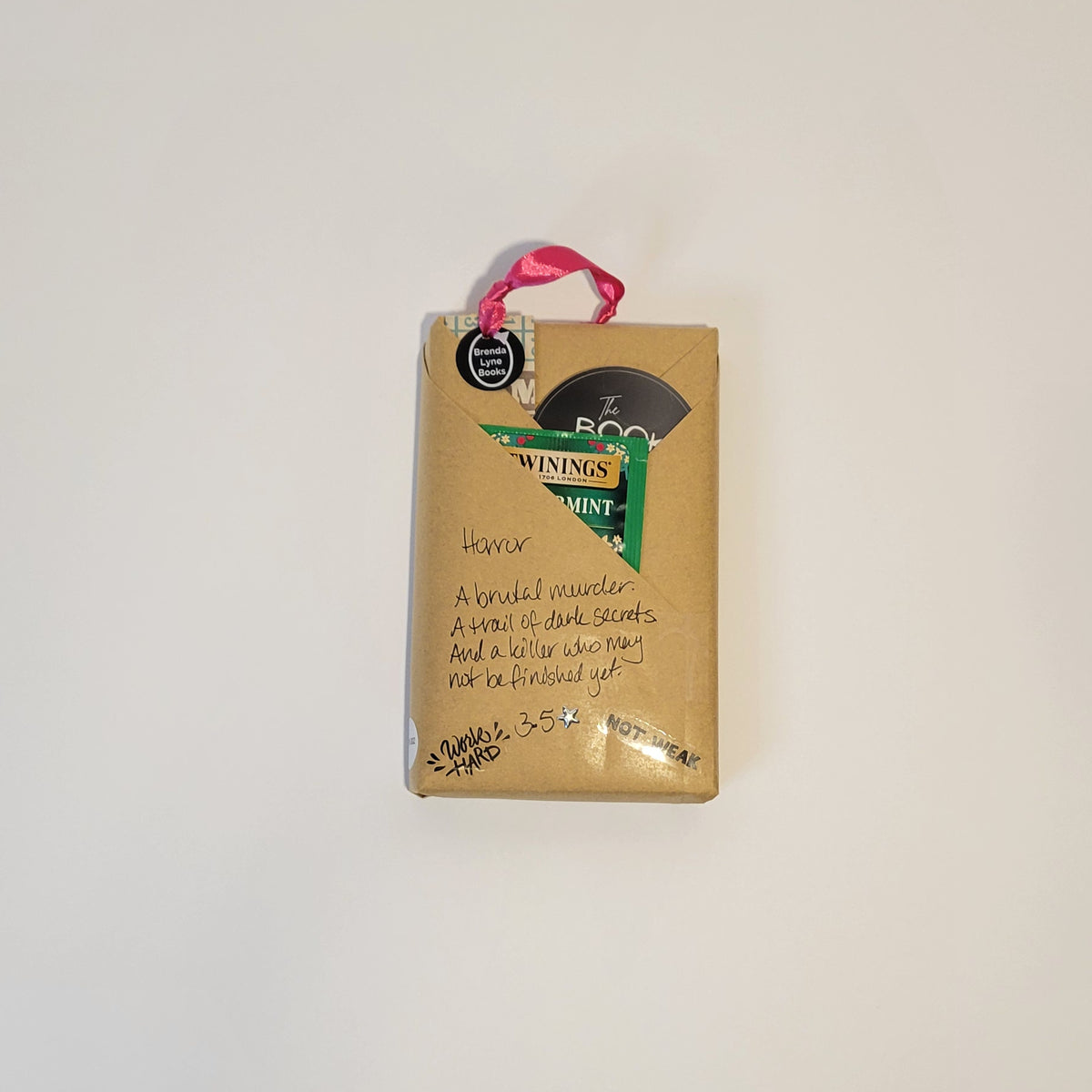 Paperback book wrapped in brown paper with writing on it and goodies tucked inside.