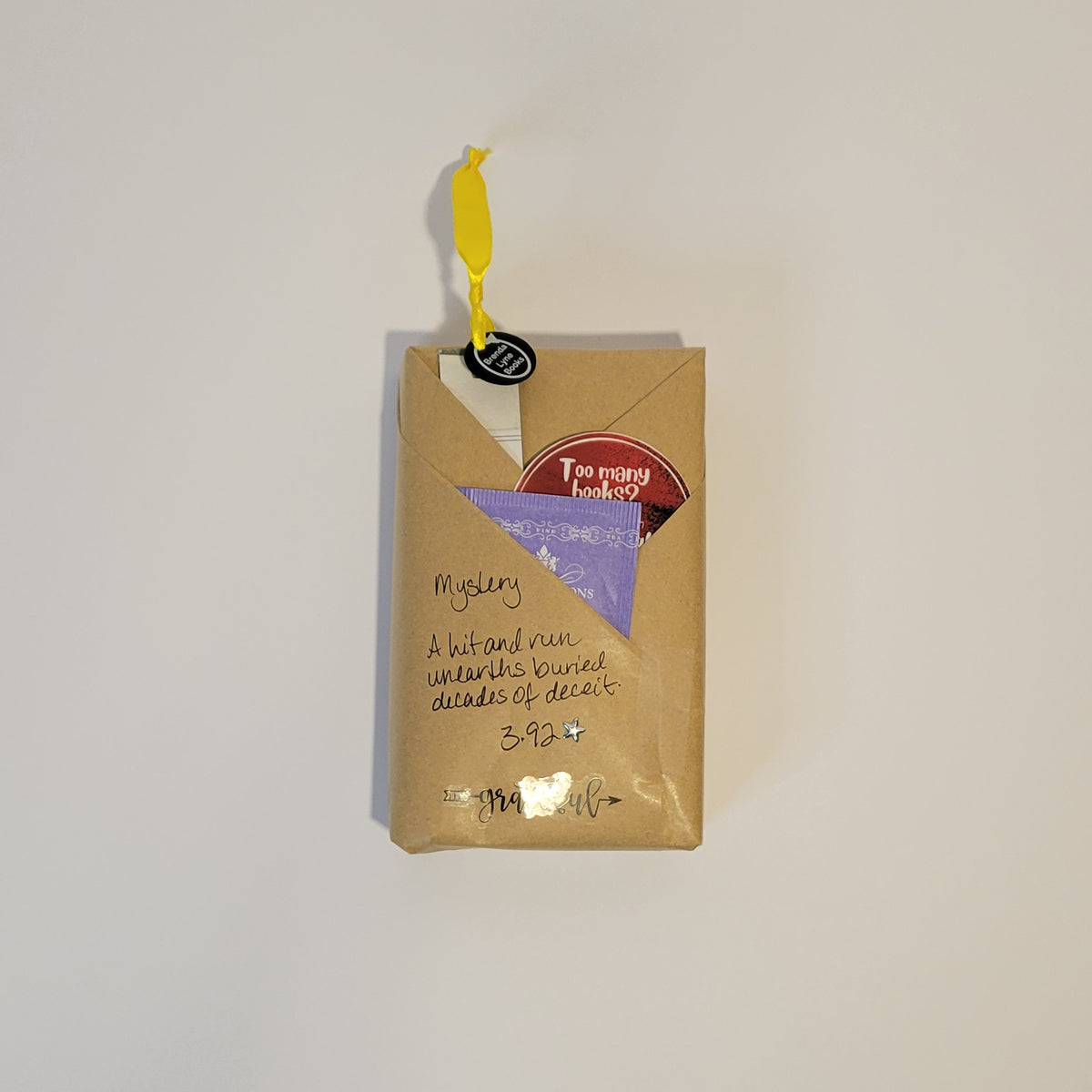 Paperback book wrapped in brown paper with writing on it and goodies tucked inside.