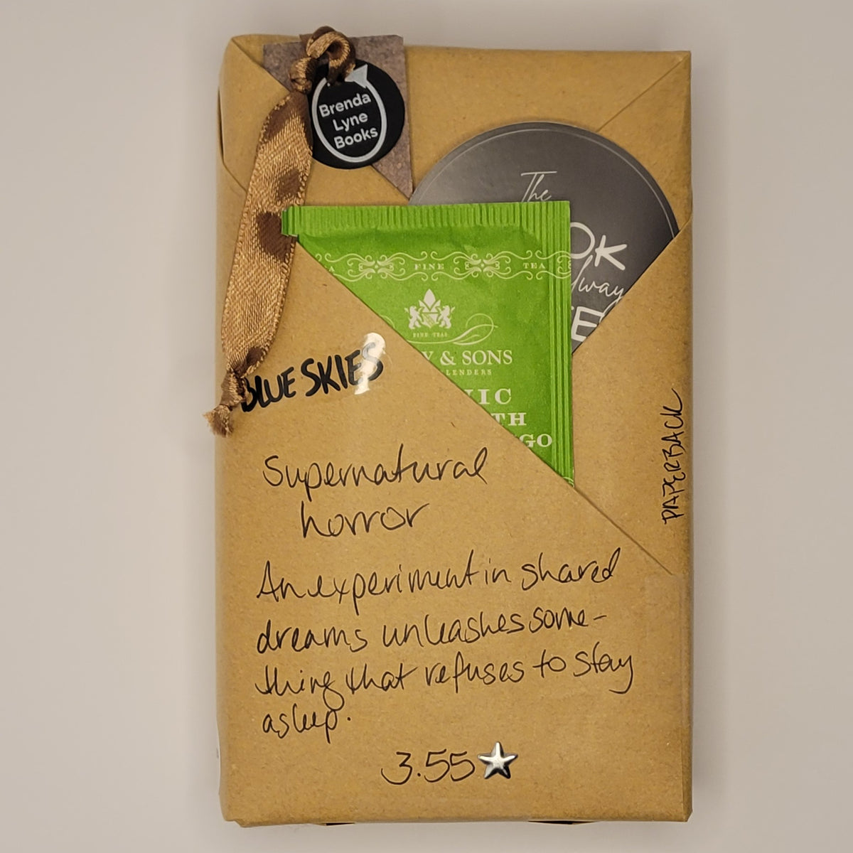 Paperback book wrapped in brown paper with writing on it and goodies tucked inside.