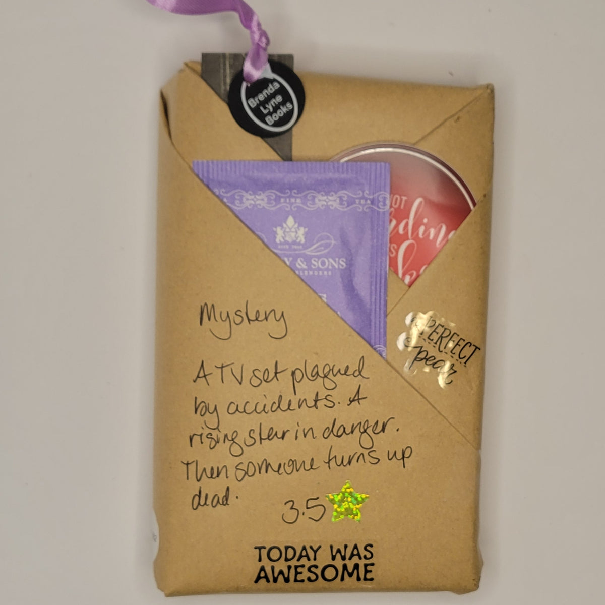 Paperback book wrapped in brown paper with writing on it and goodies tucked inside.