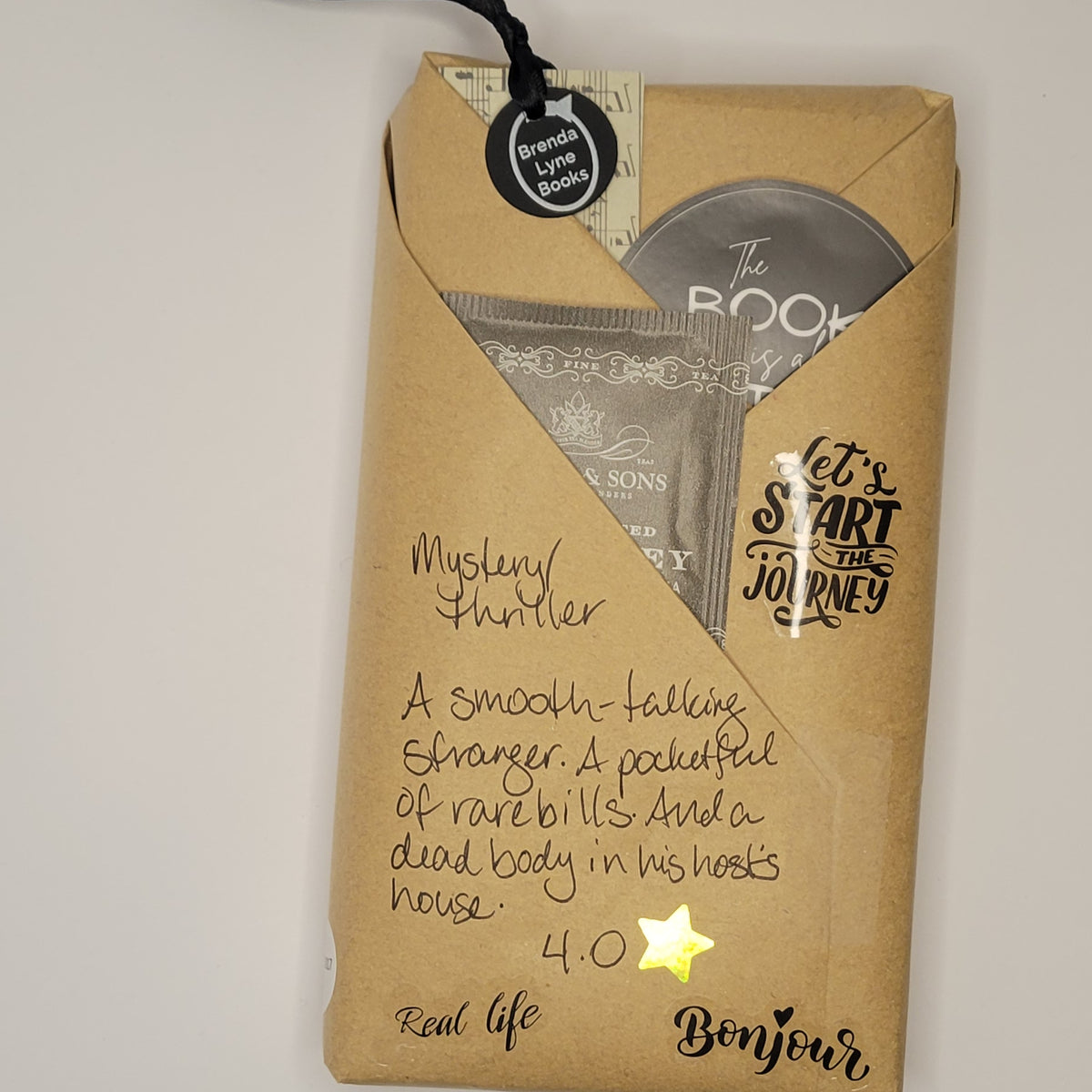 Paperback book wrapped in brown paper with writing on it and goodies tucked inside.