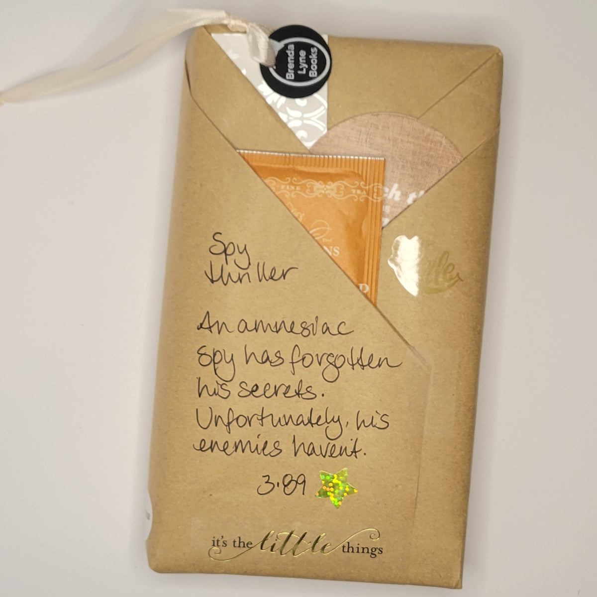 Paperback book wrapped in brown paper with writing on it and goodies tucked inside.
